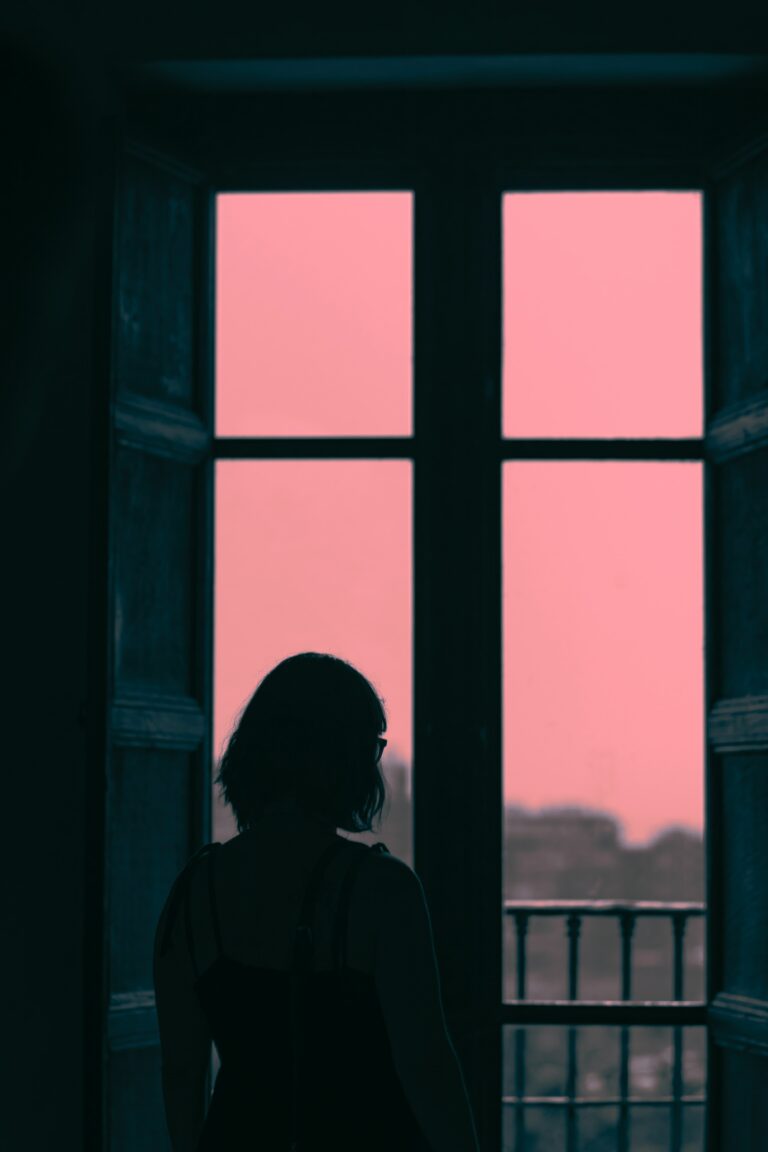 A girl standing alone looking out a window