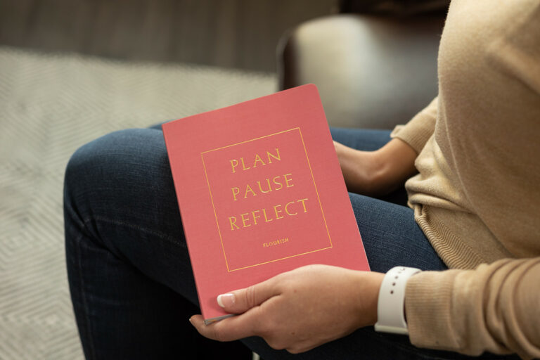 Pink journal that says, "Plan, pause, reflect" on the cover, held by DBT therapist Dr. Desirae Allen at Cincinnati Center for DBT. DBT skills are helpful in maintaining sobriety from alcohol and drugs.