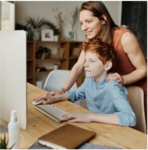 Mother smiling while helping child on computer