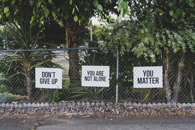 Signs along a fence reading "Don't give up", "You are not alone", "You matter"