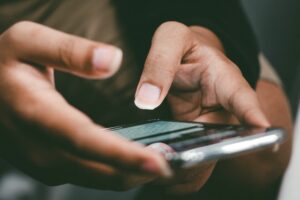 A person holding a phone considering what they will reply back with via text