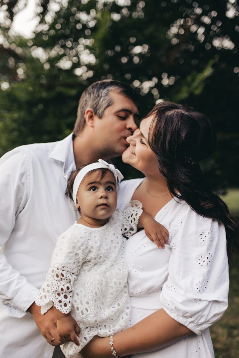A new family dressed in white, with their baby girl assuming their new roles as family