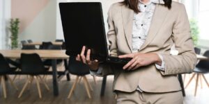 Woman in a tan suit holding up a laptop so she can view data after conducting a parental assessment