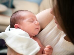 A new mother in white holding her newborn baby