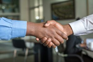 Two individuals in long sleeved dress shirts shaking hands