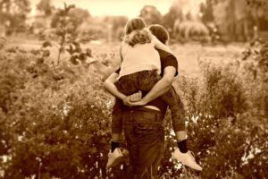 Father spending time with his daughter by carrying her on his back while on a walk in nature